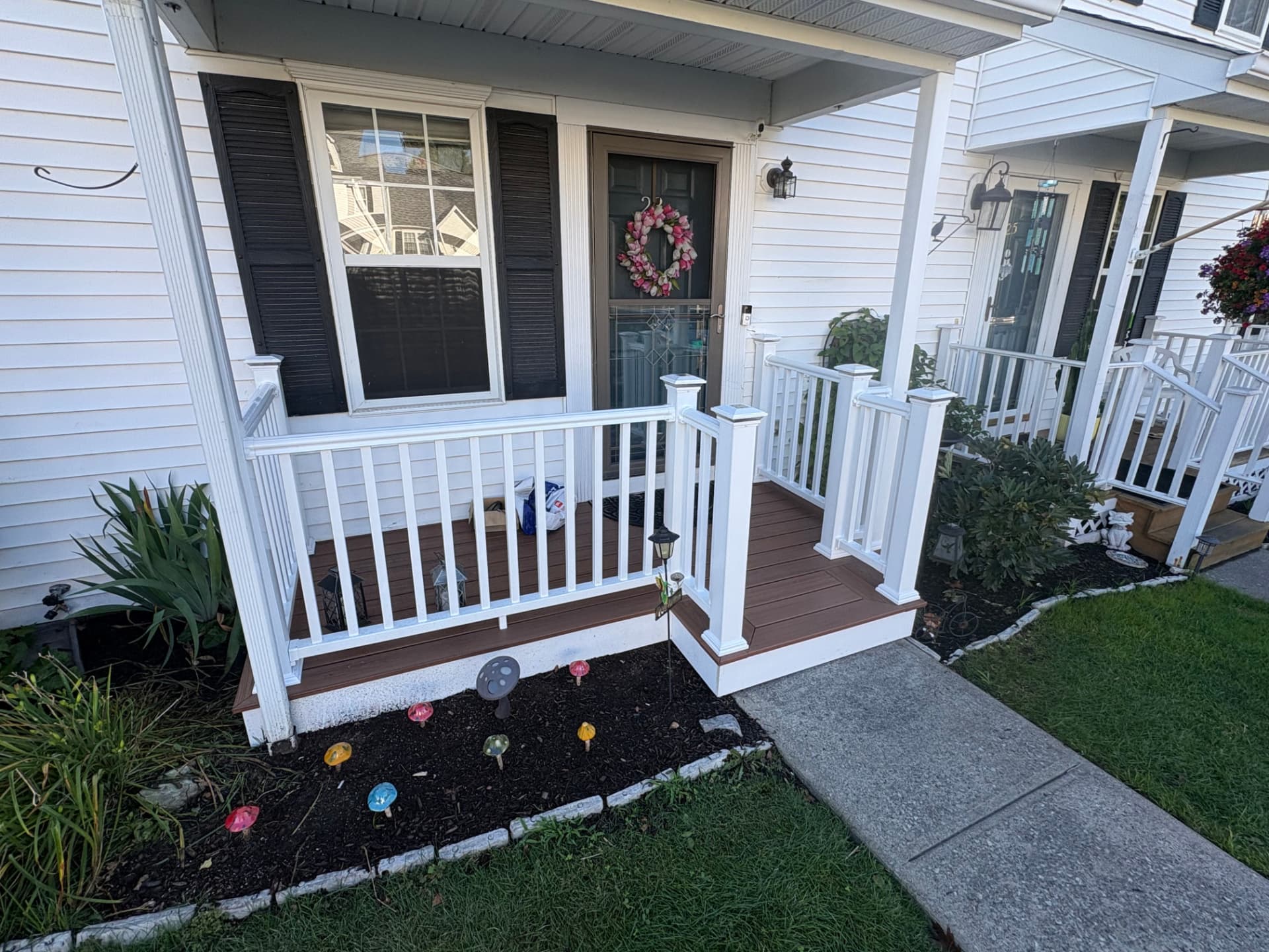 Covered front porch with white vinyl railing, solar post caps and brown composite decking